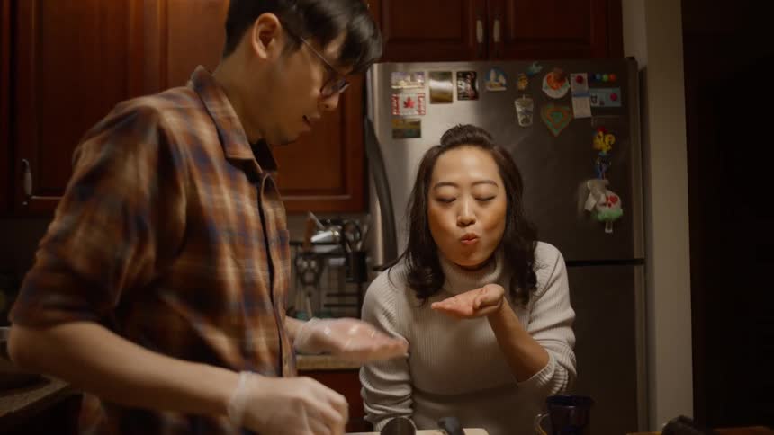 A couple cooks together in the kitchen at home and man feeds woman food