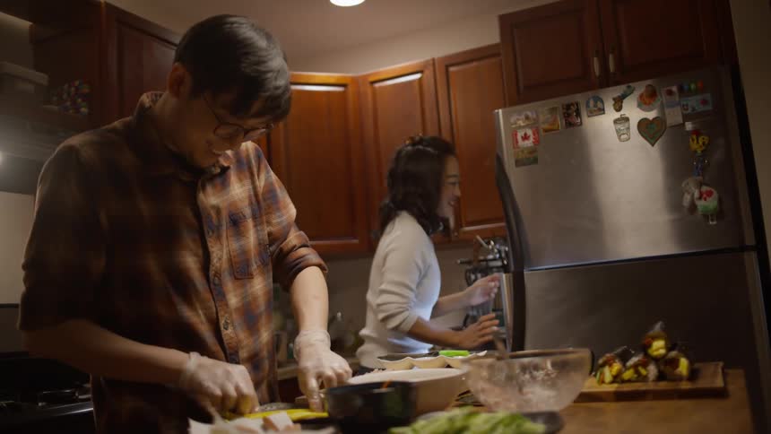Couple cooking dinner in the kitchen at home and laughing