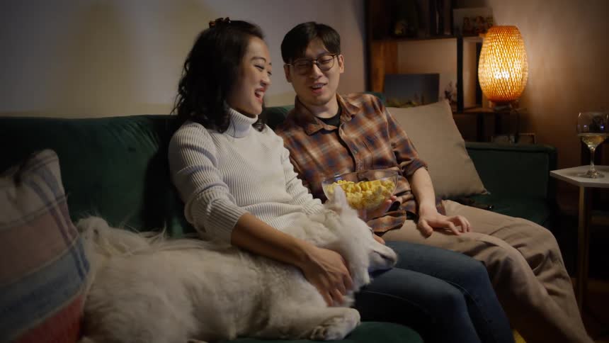 Couple sitting with a dog eating popcorn at night