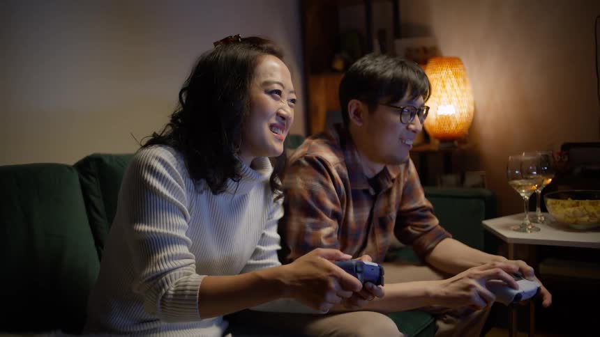 Man and woman sitting on the couch playing video games with controllers and having fun