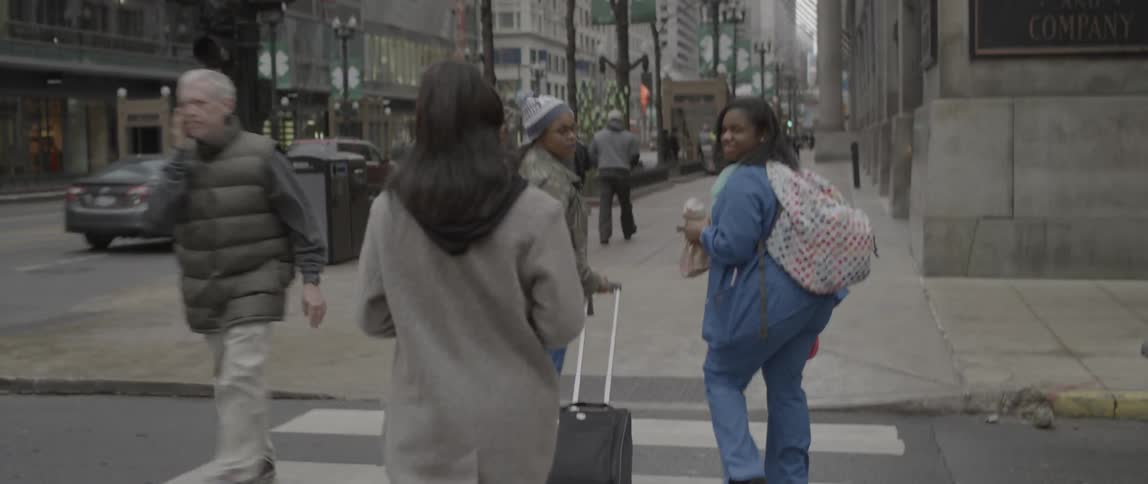 Pedestrians walk on a city street and sidewalk