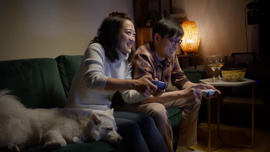 A man and a woman playing video games while a dog sleeps on the couch