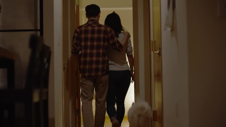 Couple walking away entering a room with the dog following closely behind