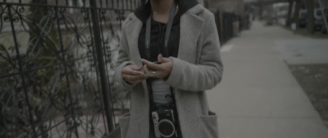 A woman is walking as she puts a photo in her pocket