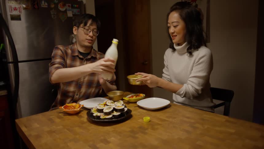 Couple sitting at a table serving each other toasting and drinking a beverage