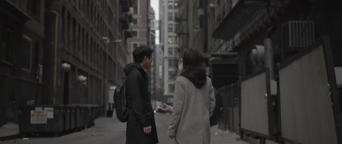 A woman talks with two men in an alley