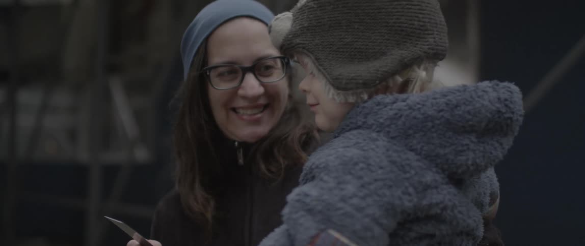 A child in a woman's arms gets a high five from another person