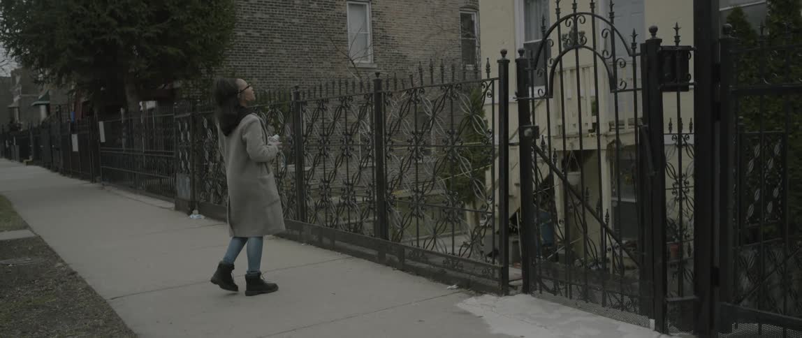 A woman walks past a home and stops to take a photo