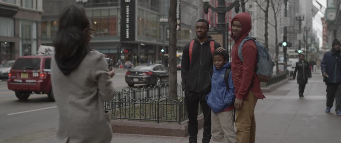 Three people pose for a photograph on a city street