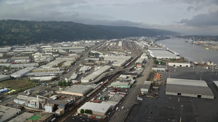 Aerial panorama of an industrial area by a lake surrounded by mountains