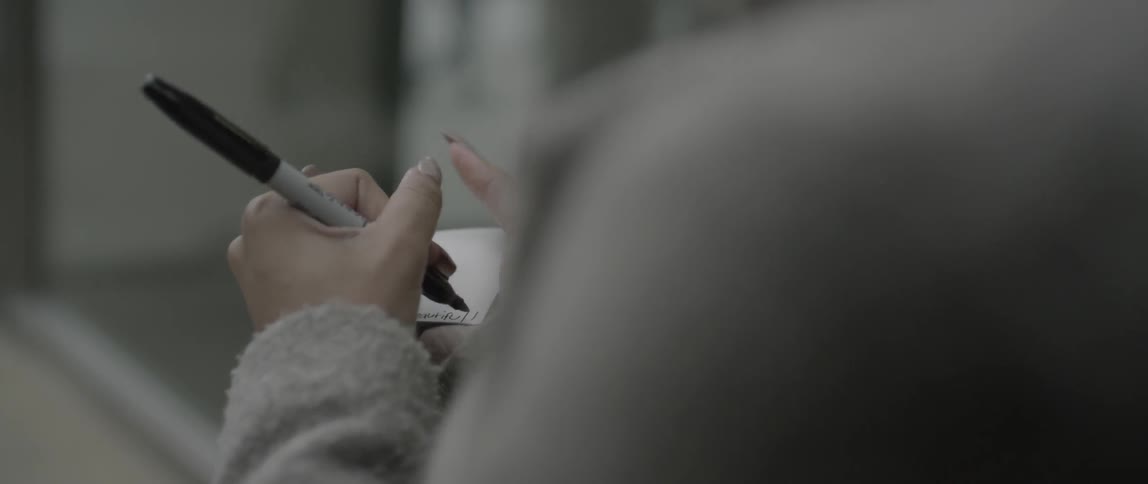 A woman is writing with a marker on a photograph then hands it to a woman