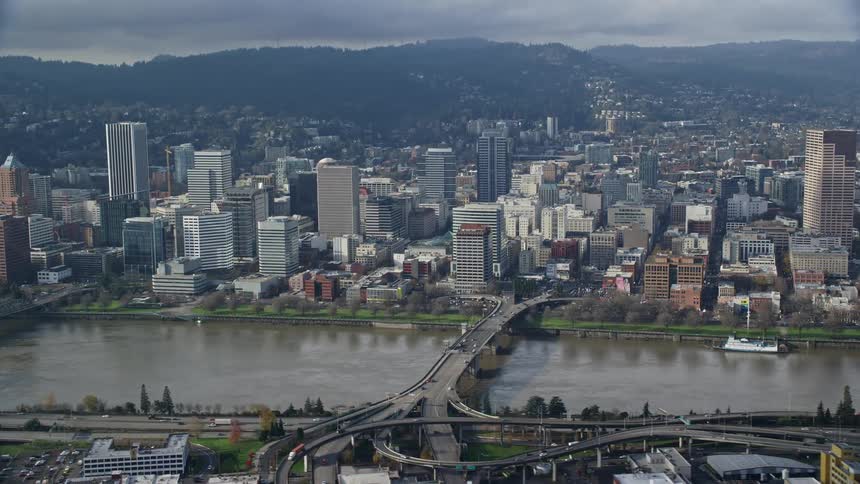 A neighborhood in a city with tall buildings that face a large river with bridges running over it