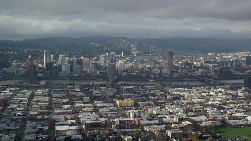 Aerial view of a large city with numerous warehouses buildings and a river running through the middle on a cloudy day