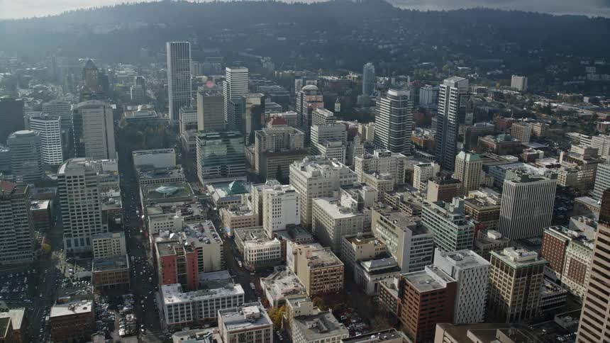 Aerial shot of a large city featuring buildings skyscrapers and a river cutting through under the bright sunlight