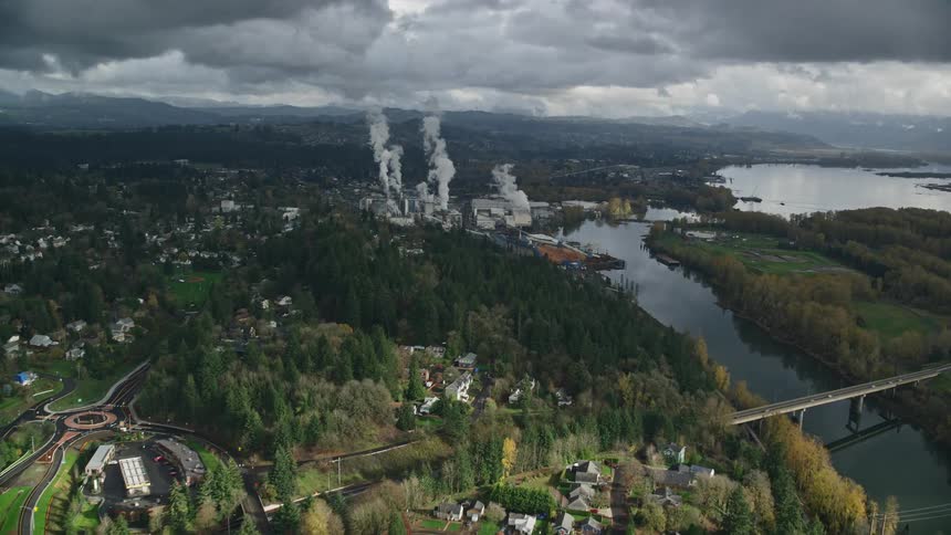 Aerial view of an urban city with abundant vegetation a river and a factory on a cloudy day