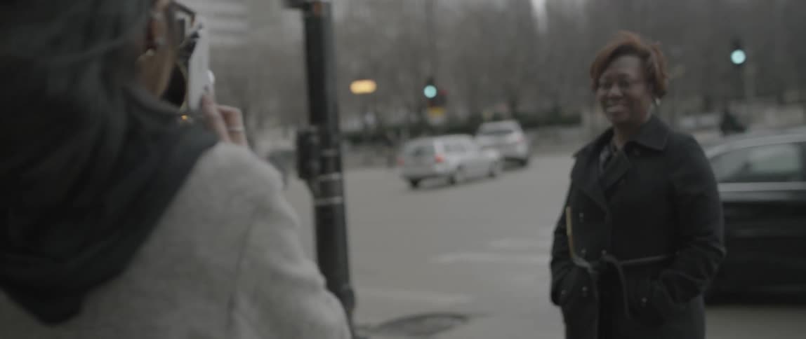 A woman is crossing a street and is approached by a woman