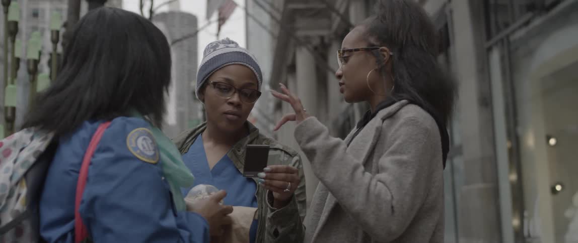 Women are talking on a city street and looking at a photo