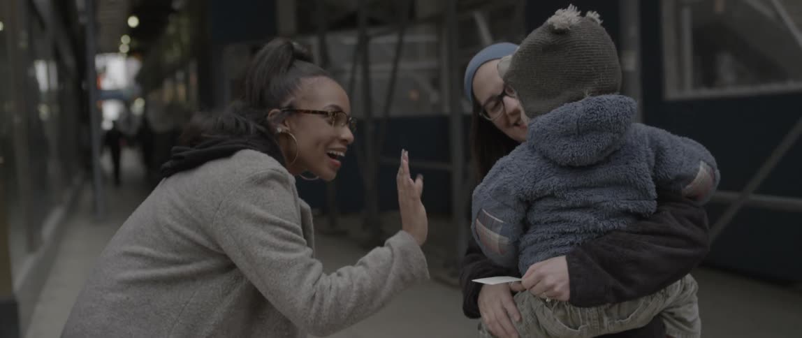 A woman writes on a photo and hands it to a woman then gives her a hug