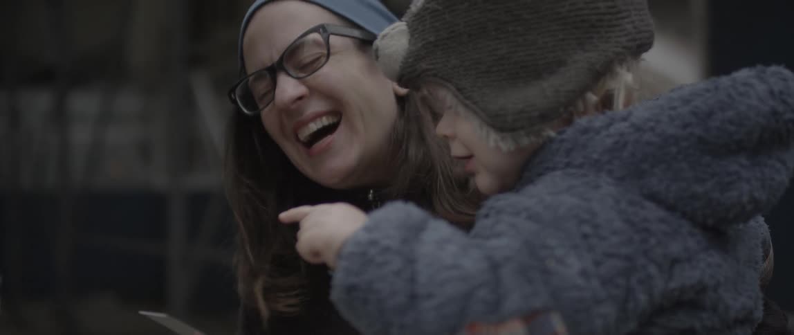 Woman and child point and smile at a book