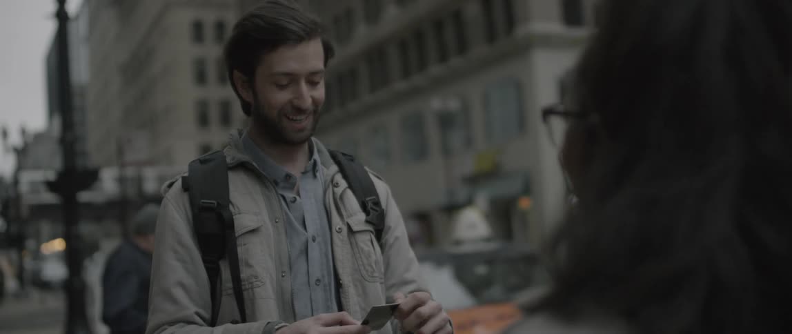 A woman hands a man a photograph and hugs him