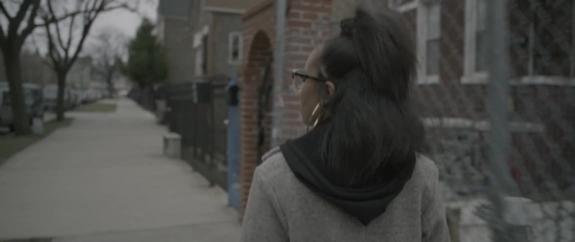 A woman walks on a sidewalk in a residential area