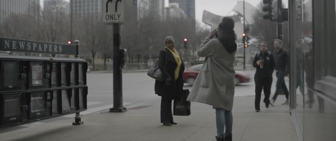 A woman takes another woman's picture on the street corner