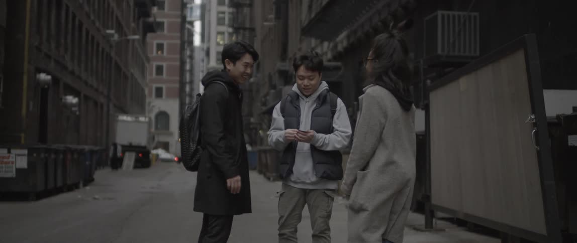 Three people look at a photograph in an alley