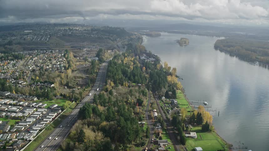 A raod assing through a sub urban town with a lake on the side and tress everywhere