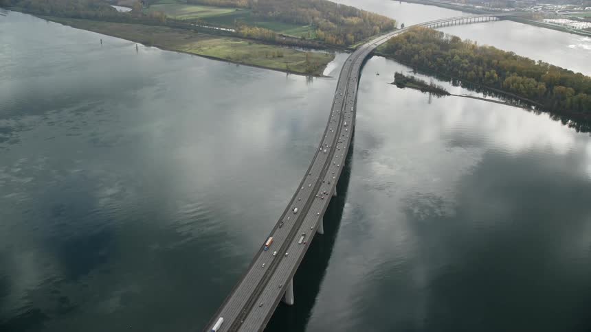 Aerial panorama of a long bridge spanning a lake next to a city
