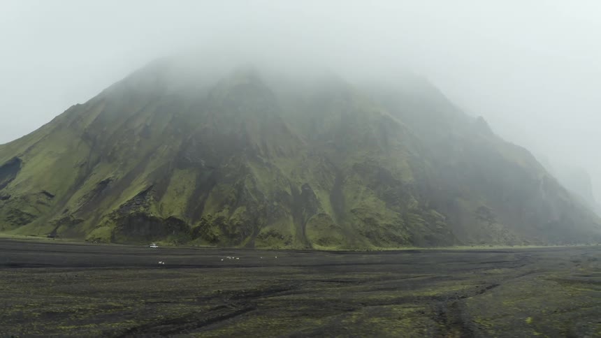 Aerial of a car in the landscape of plains and mountains on a cloudy day