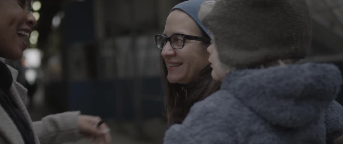 A woman holding a child hugs another woman and walks away