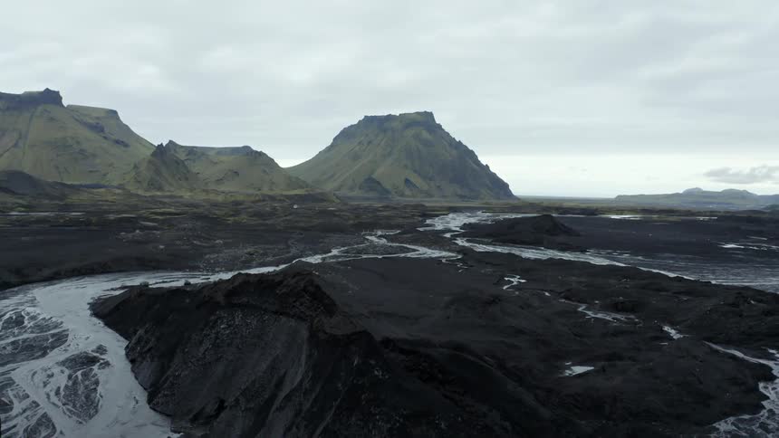 Aerial panorama of mountains and peaks with rivers passing through black soil