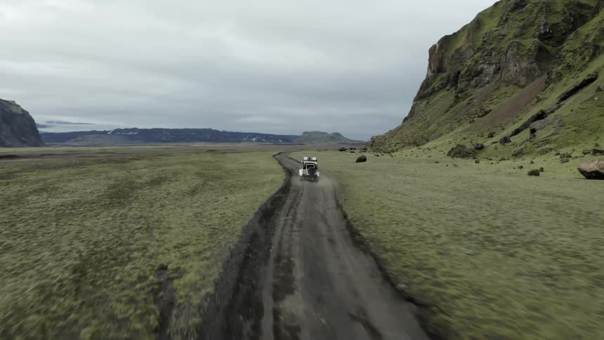 Jeep driving on a dirt road next to mountains