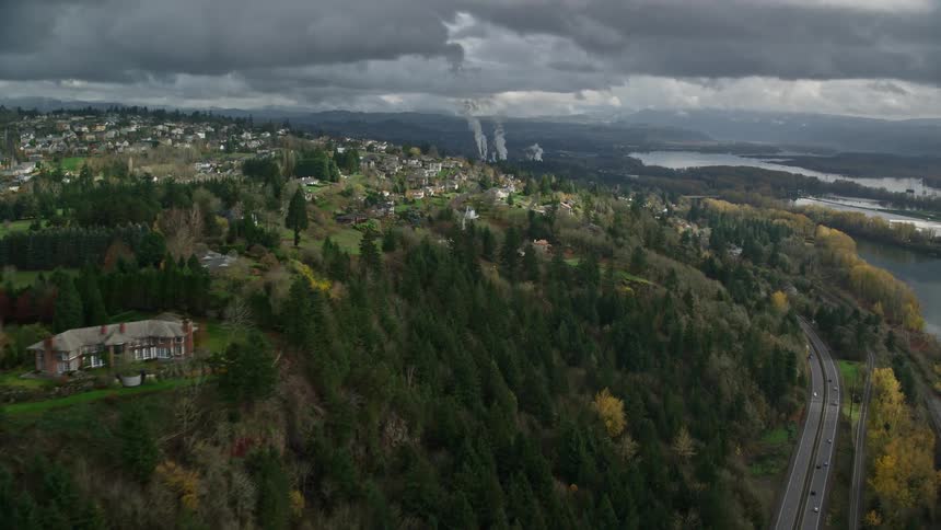 Aerial panorama of an urban and residential city amidst hills along a river on a cloudy day