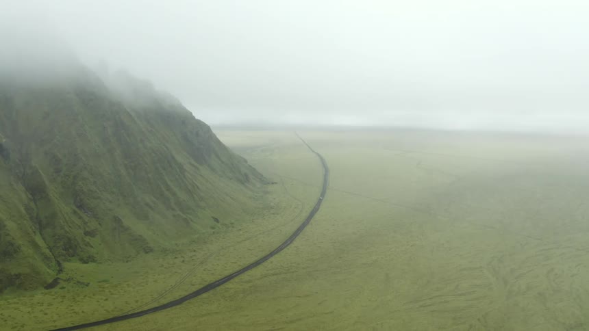 Aerial view of a road next to a mountain on a hazy day