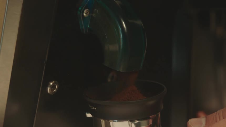 Extreme closeup of a machine pouring coffee into a small cup