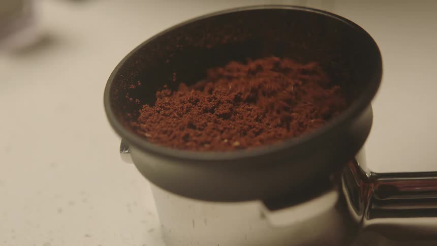 Closeup of a handle with coffee grounds being stirred