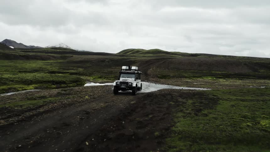 A sports car on a dirt road in the hills landscape during sunset