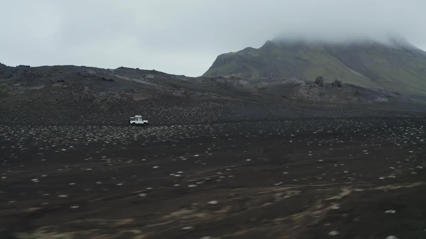 Jeep traveling alongside mountains on a dirt road