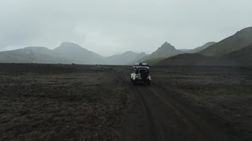 A car driving along a dirt road with a mountainous landscape