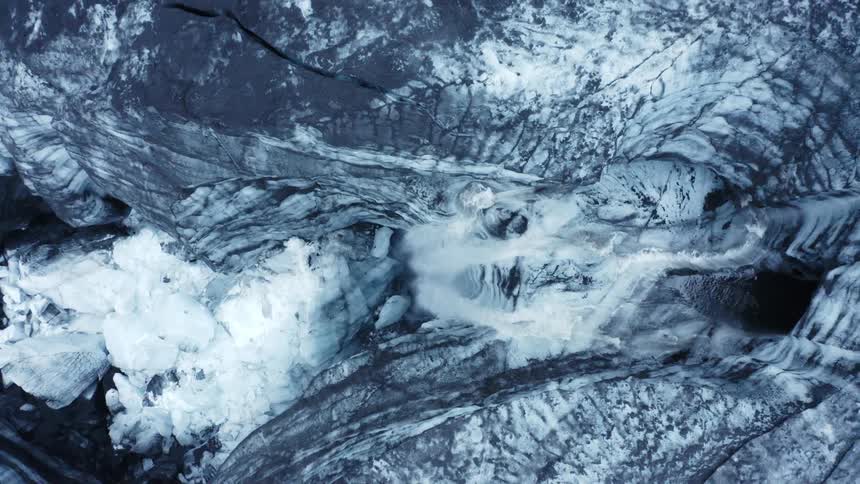 Aerial view looking down on glacier with a waterfall and scattered ice