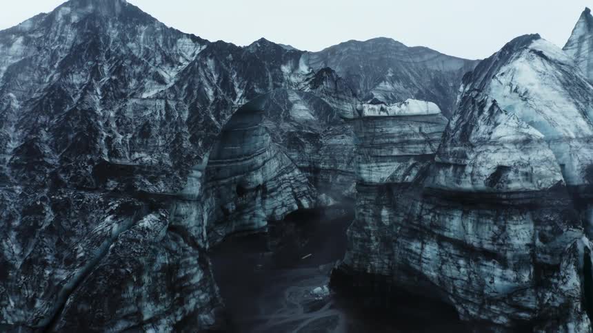 View of ice cave with cliff formations under a cloudy sky