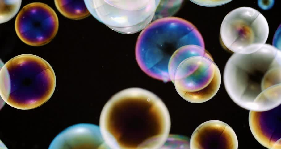 Some soap bubbles with reflections are in an environment with a black background