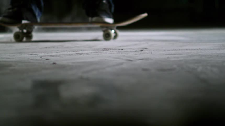 Close up of a skateboard sliding over concrete