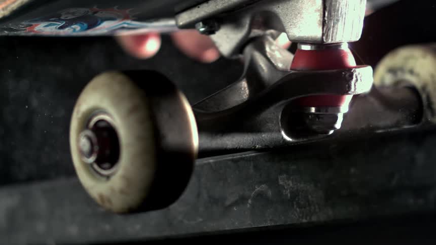 Closeup of a skateboard rolling over a metal edge in slow motion
