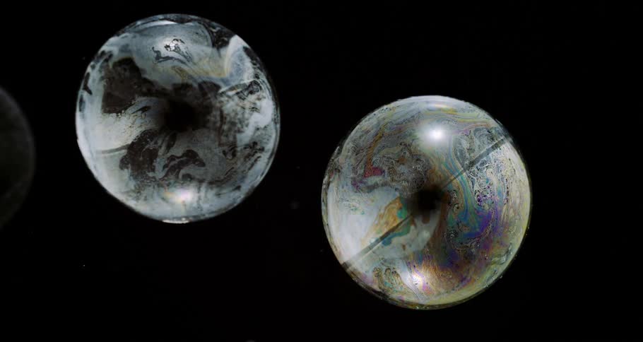 Translucent orbs with an oily surface float in the darkness