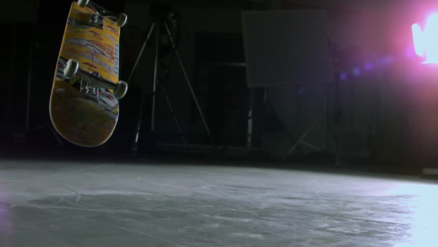 Skateboarder performing an aerial trick in a studio in slow motion