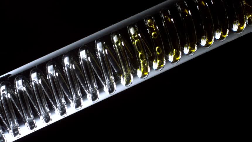 Yellow liquid flows along spiral enclosed in tube leaving a residue
