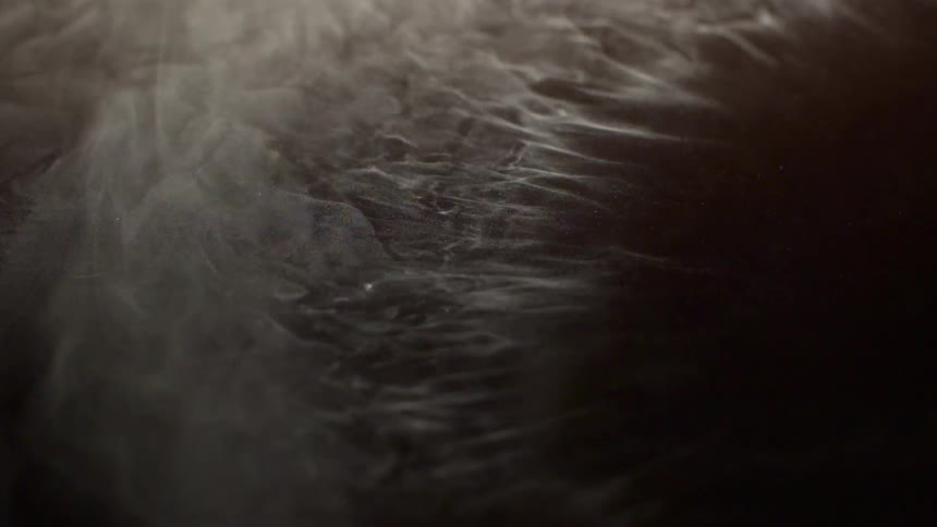 Light dusting of snow blows away from a dark surface