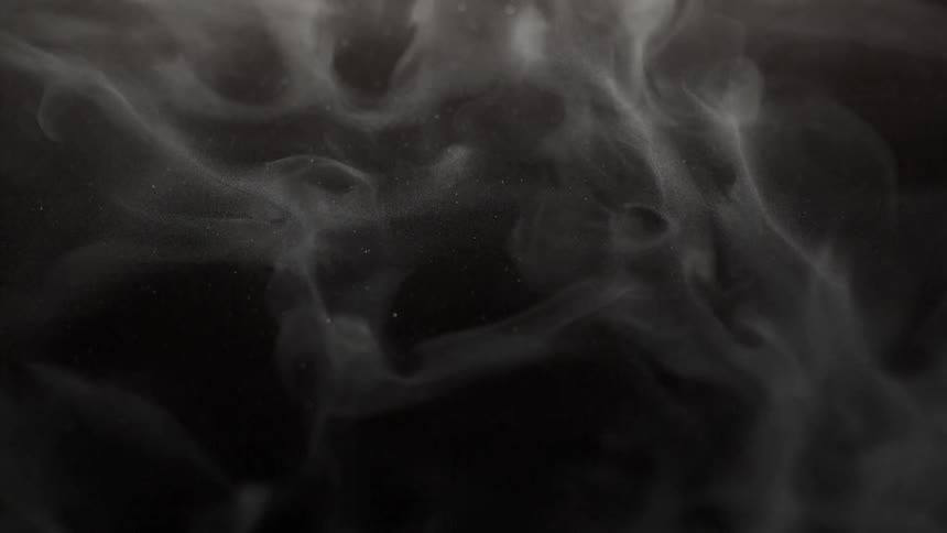 Wispy gray clouds partially obscure stars in the night sky
